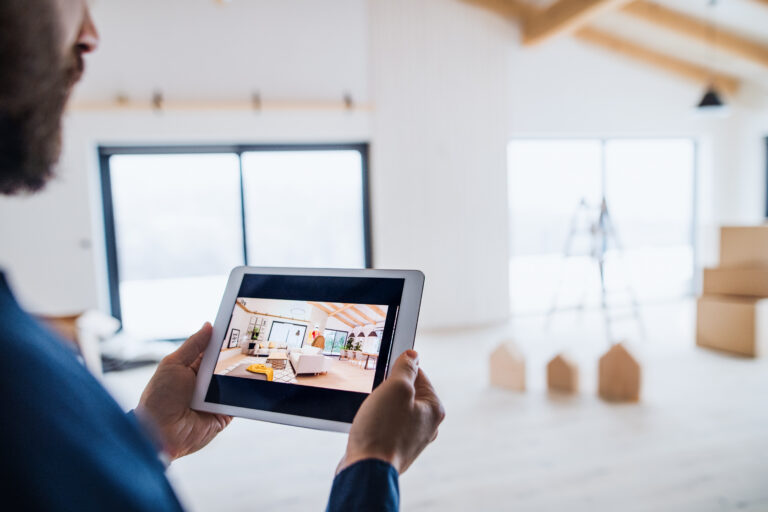 Ein Mann im Anschnitt hält ein Tablet in den Händen und schaut sich Interior-Designs an.